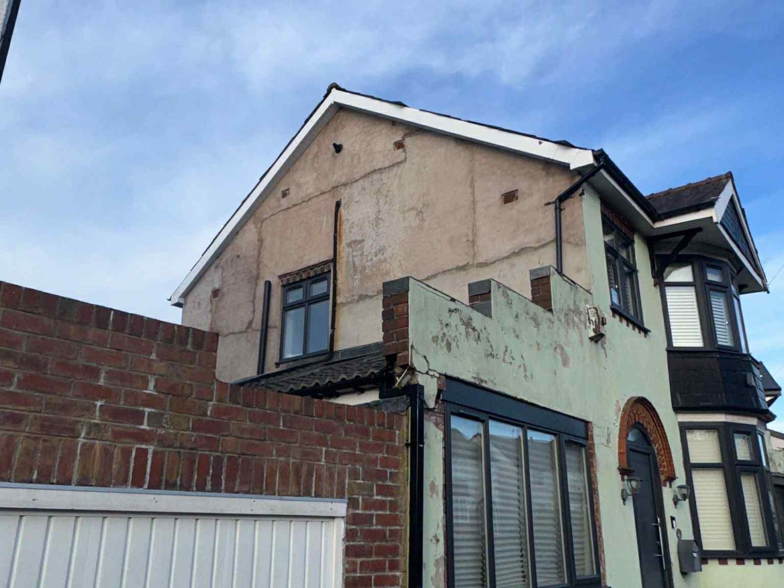 Cracked gable wall with failing render before the work