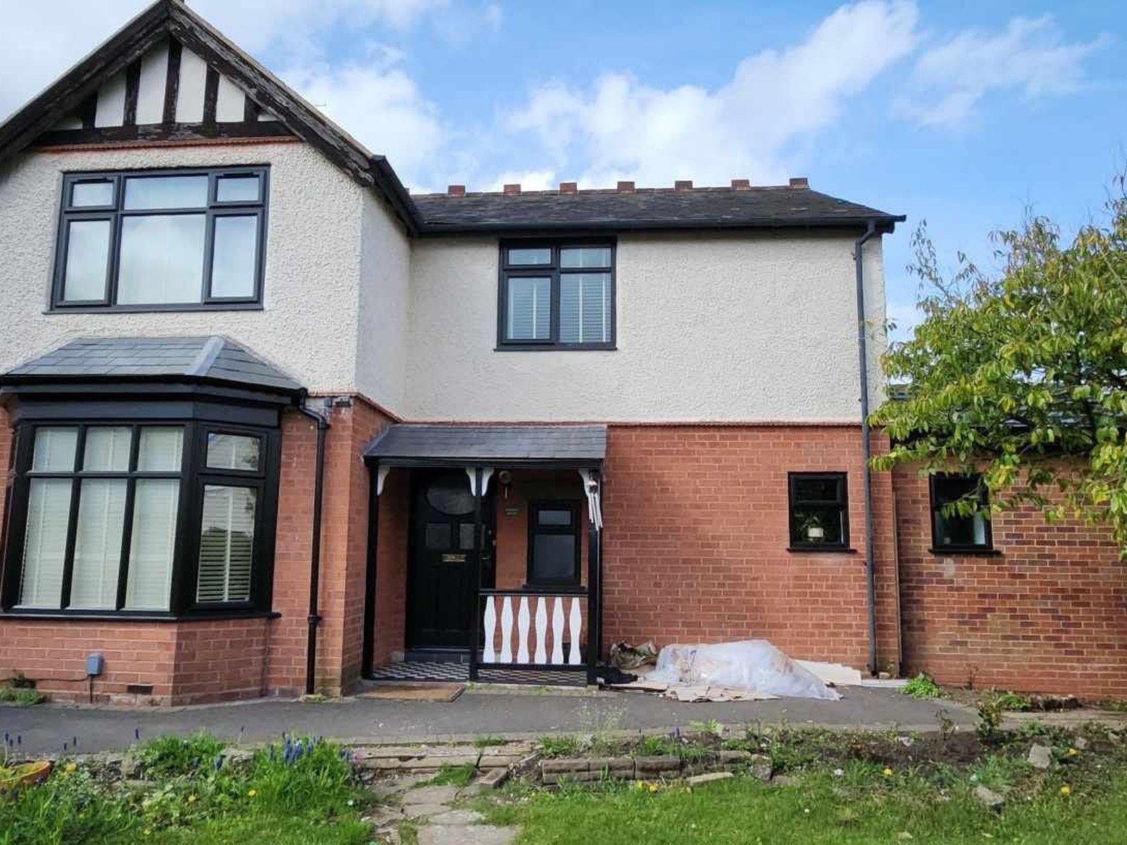 Semi-detached house with weathered pebble dash to the upper walls before rendering