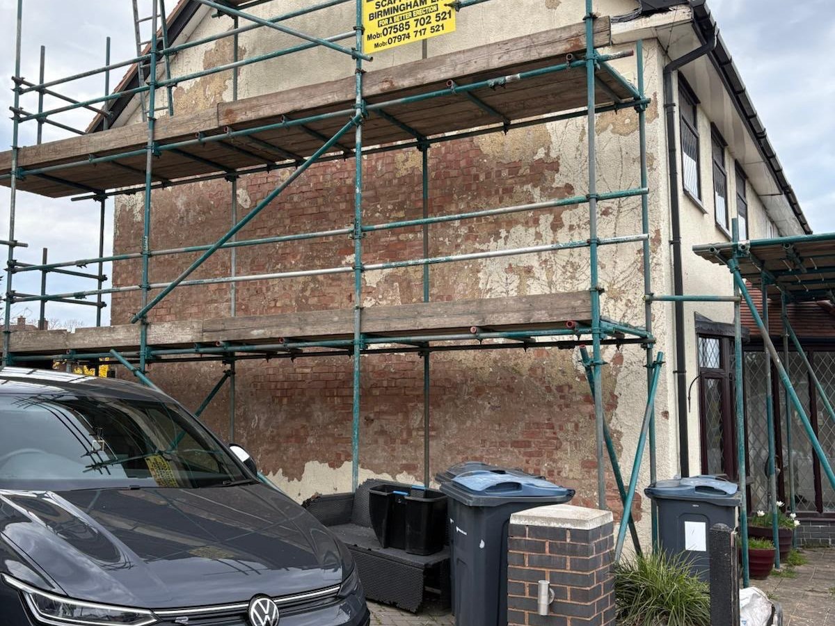 Gable end with blown, peeling render exposing brickwork before the work